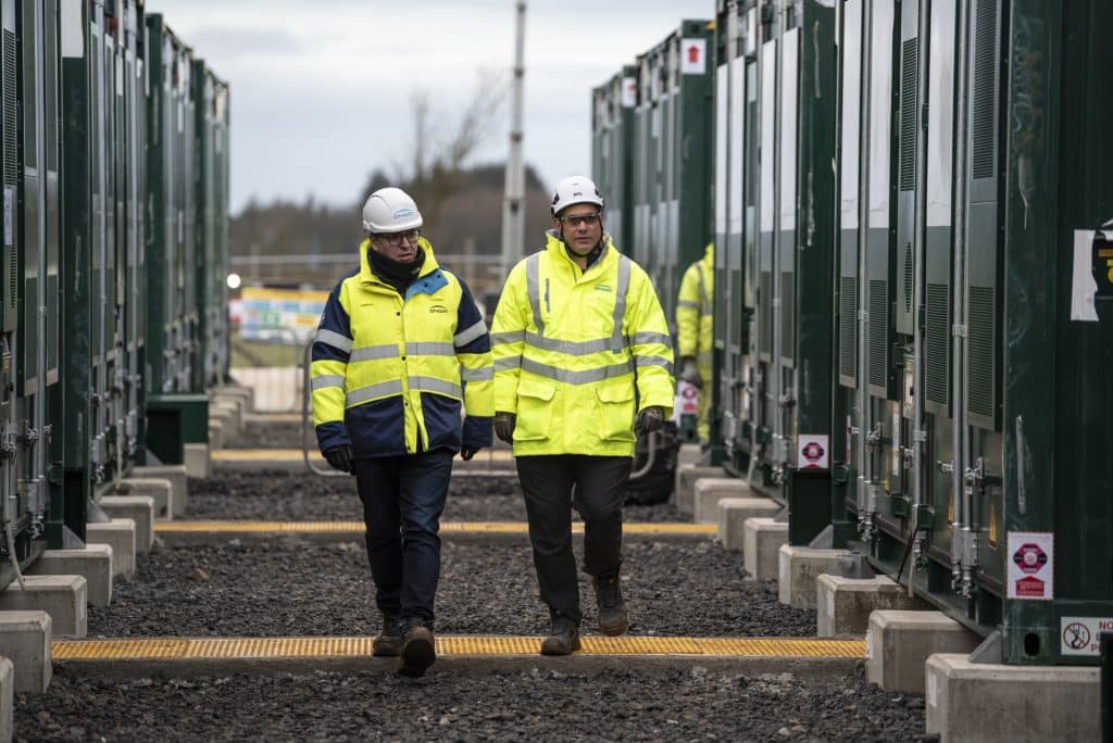 Two people walking alongside battery energy storage systems in scotland