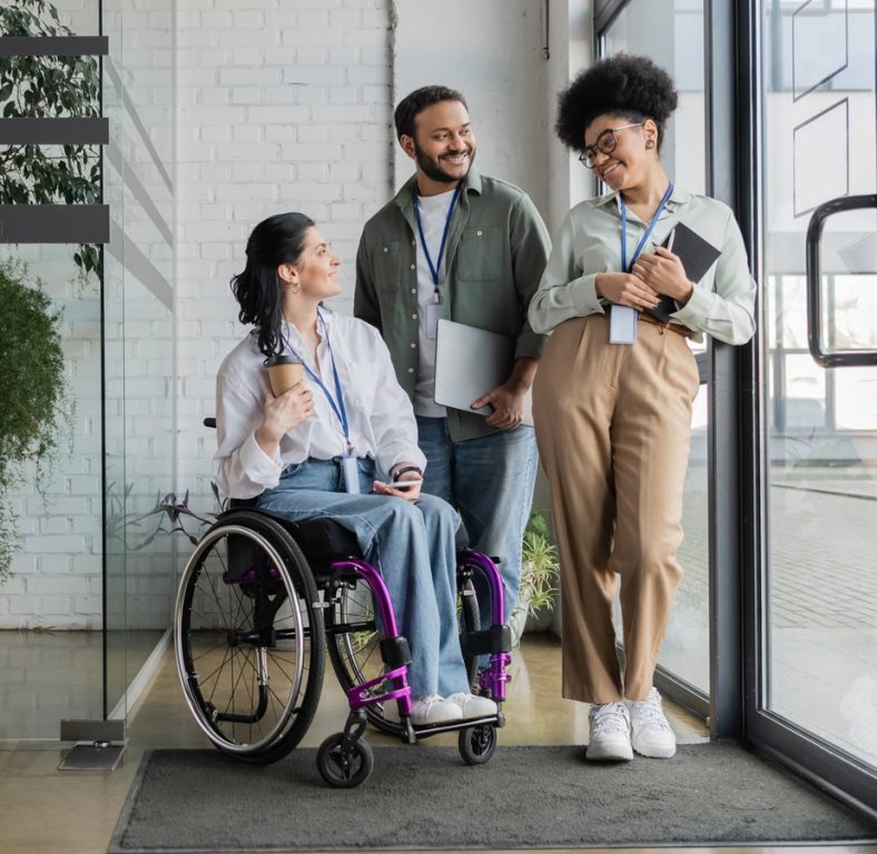 group shot of diverse business people, disabled woman on wheelchair chatting with colleagues