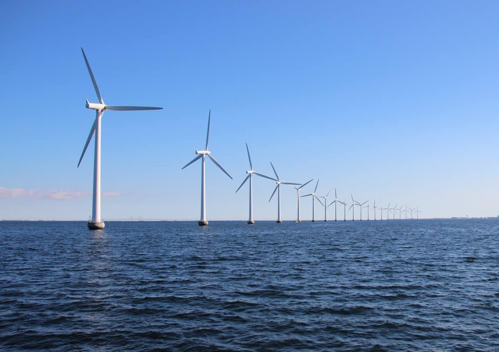 Perspective line of ocean wind mills with dark water and sky