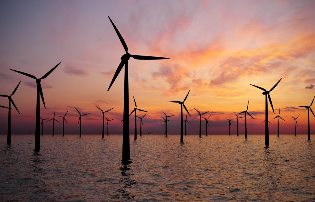 Wind turbines in sea at sunset