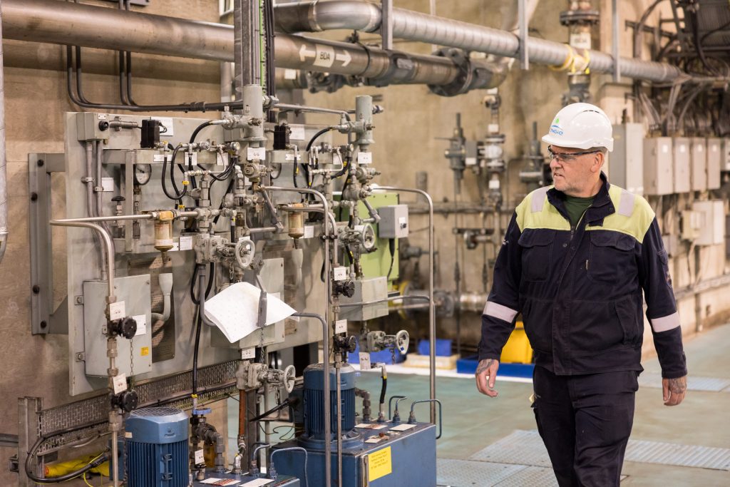 Employee walking with machinery in background