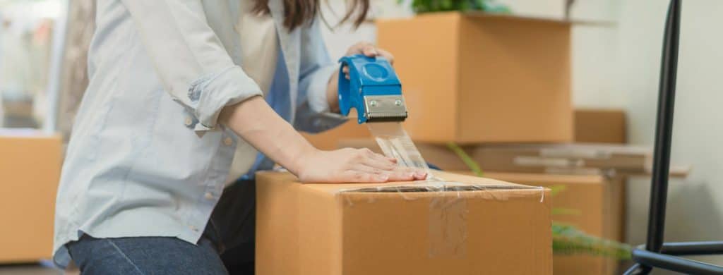 Focus hand of business woman celotaping packing box for moving out