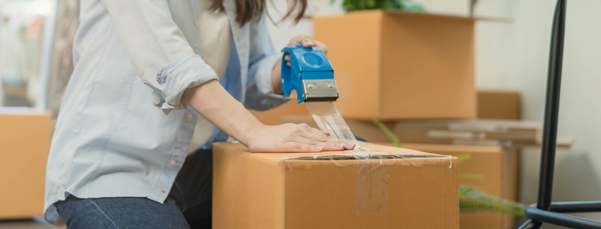 Focus hand of business woman celotaping packing box for moving out